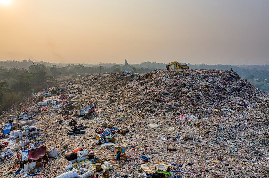 A large pile of black plastic rubbish bags is stacked against an exterior wall with a grid of beige tiles. The bags appear to be filled with various household waste and are piled irregularly, some leaning or resting on others. Several clear plastic water bottles are visible among the bags, some partially crushed or flattened, suggesting previous use and disposal. In the background, part of a metallic urban structure or pole reflects sunlight, and a cloudy sky is partially visible at the top left of the image. Red graffiti with the word 'XEND' is spray-painted on the tiled wall behind the rubbish, indicating an urban environment. The scene suggests an instance of private waste collection or on-site rubbish removal, potentially managed by Waste Removal Clapham, as evidenced by the informal nature of the waste containment and outdoor setting. The overall atmosphere is indicative of an area experiencing an accumulation of waste awaiting collection or disposal, aligning with rubbish removal services focused on bulk waste clearance.